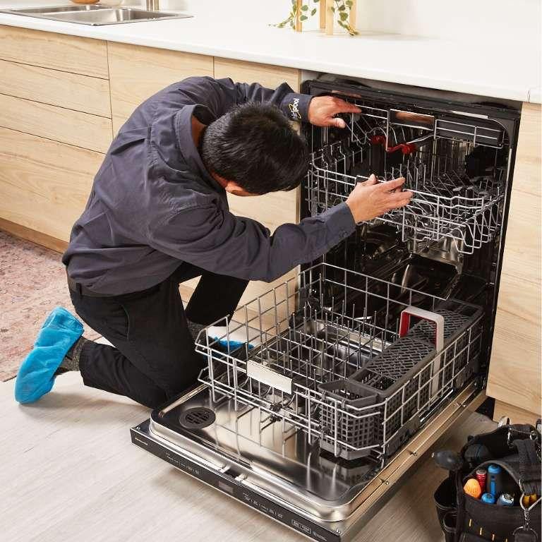 Technician diagnosing a dishwasher's pump and spray arm components