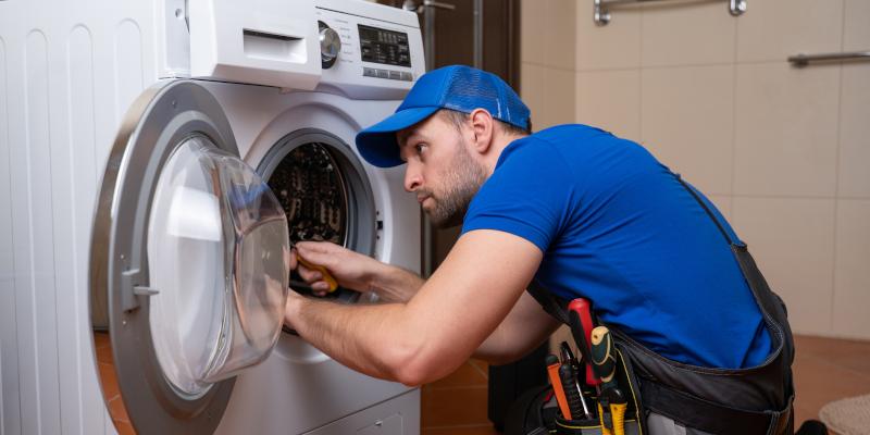 Technician repairing a clothes dryer in a Naperville, IL laundry room