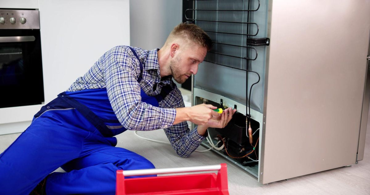 Technician repairing a refrigerator's compressor and sealed system