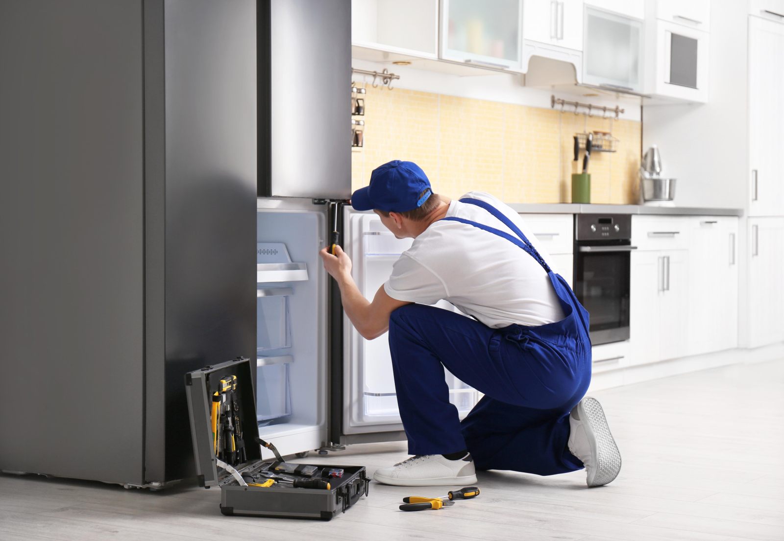 Technician repairing a refrigerator's inner panel in a Naperville, IL kitchen
