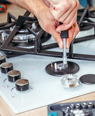 Technician performing stove and range repair work in a Naperville kitchen