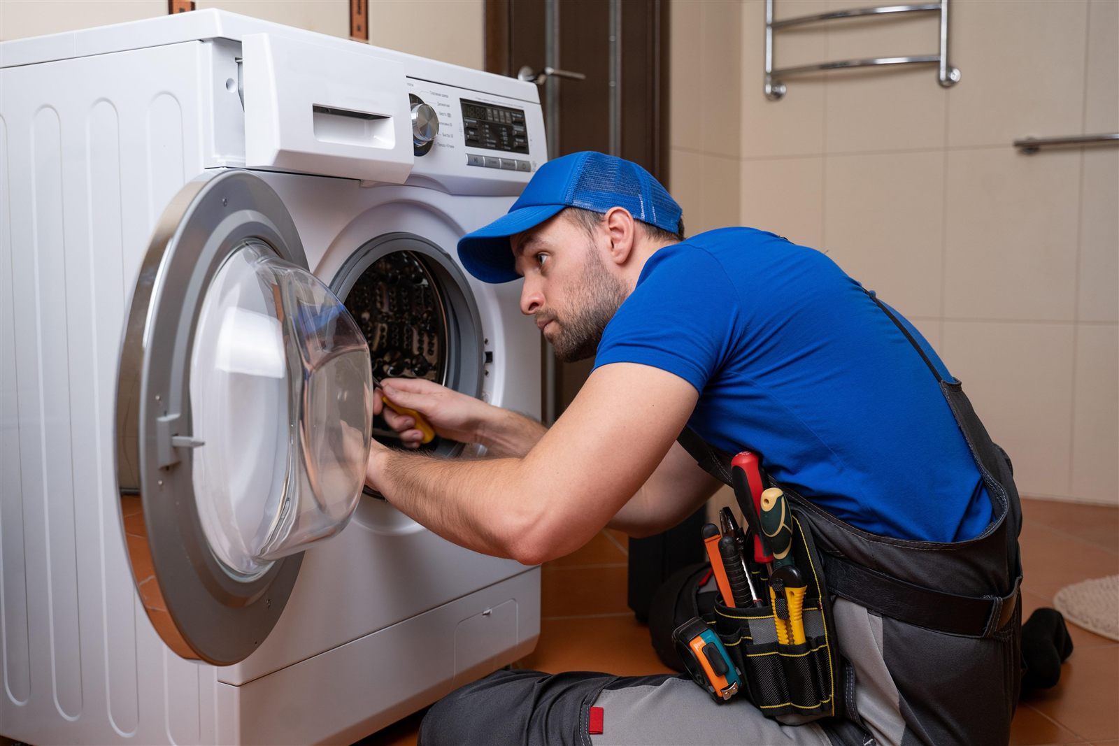 Technician repairing a washing machine in a Naperville, IL laundry room